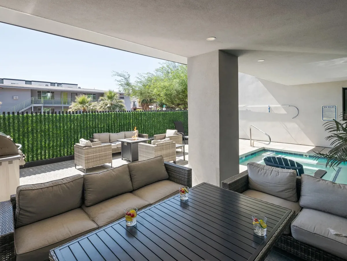 This image features a comfortable outdoor seating area beside a swimming pool, surrounded by lush greenery. The setup invites relaxation and group socializing under the sun or stars, with ample space for drinks and conversation.